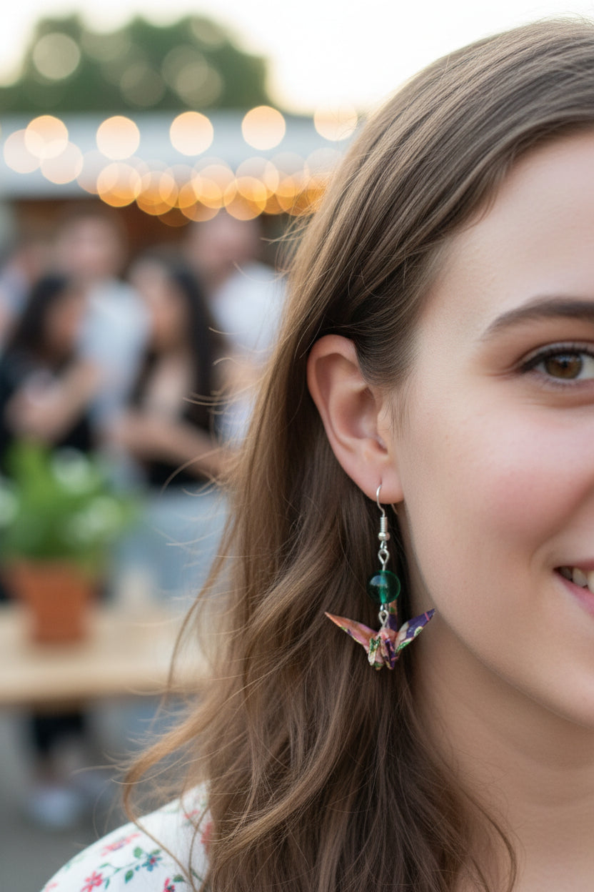 Earrings with green beads and colorful butterfly wings on a cardboard backing.